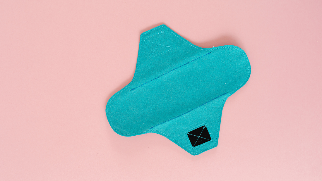 A close up of a teal-colored reusable menstrual pad made of fabric
