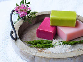Photo of colorful bars of soap on a fancy wooden soap dish. 