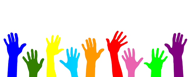 Many hands of different colors being raised in the air to symbolize an interest in volunteering
