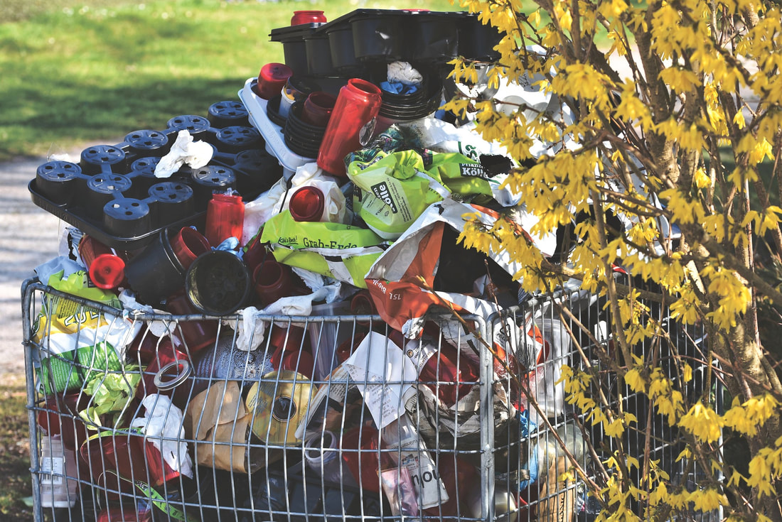 A discarded shopping cart full of single-use plastic waste has been dumped in a city park.